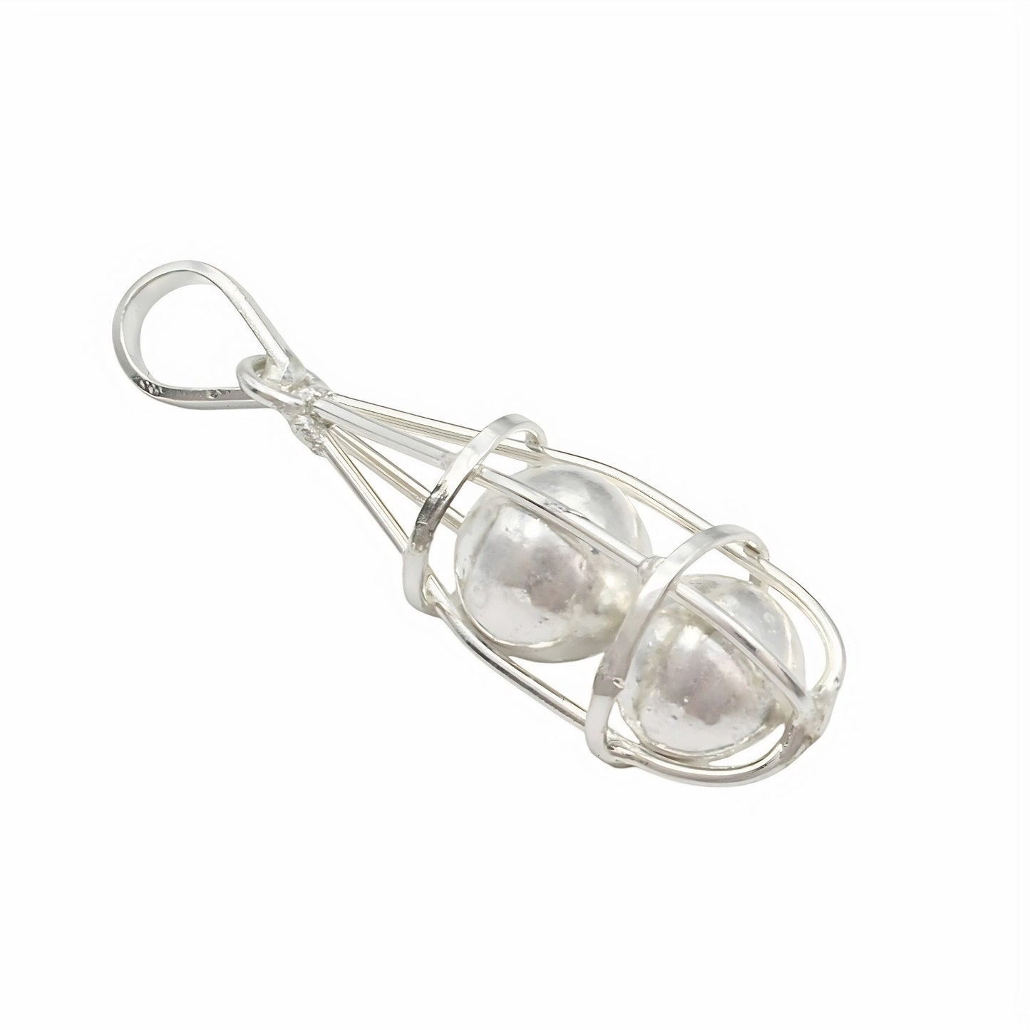 An overhead, full studio shot shows a silver pendant shaped like a wire cage holding two round silver balls, set against a solid white background.